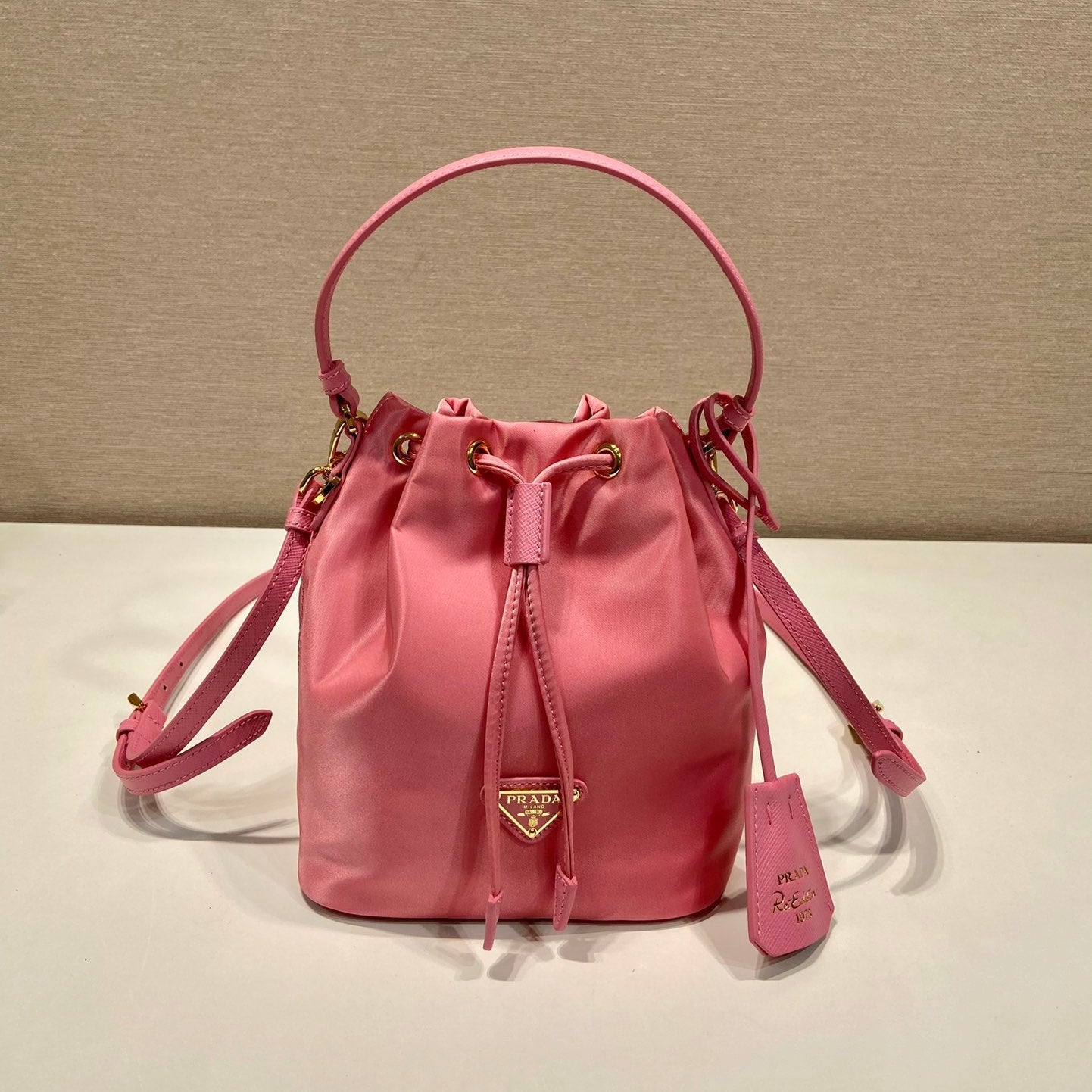 SAC SEAU 19 EN RE-NYLON ROSE BONBON ET POIGNÉE EN CUIR SAFFIANO