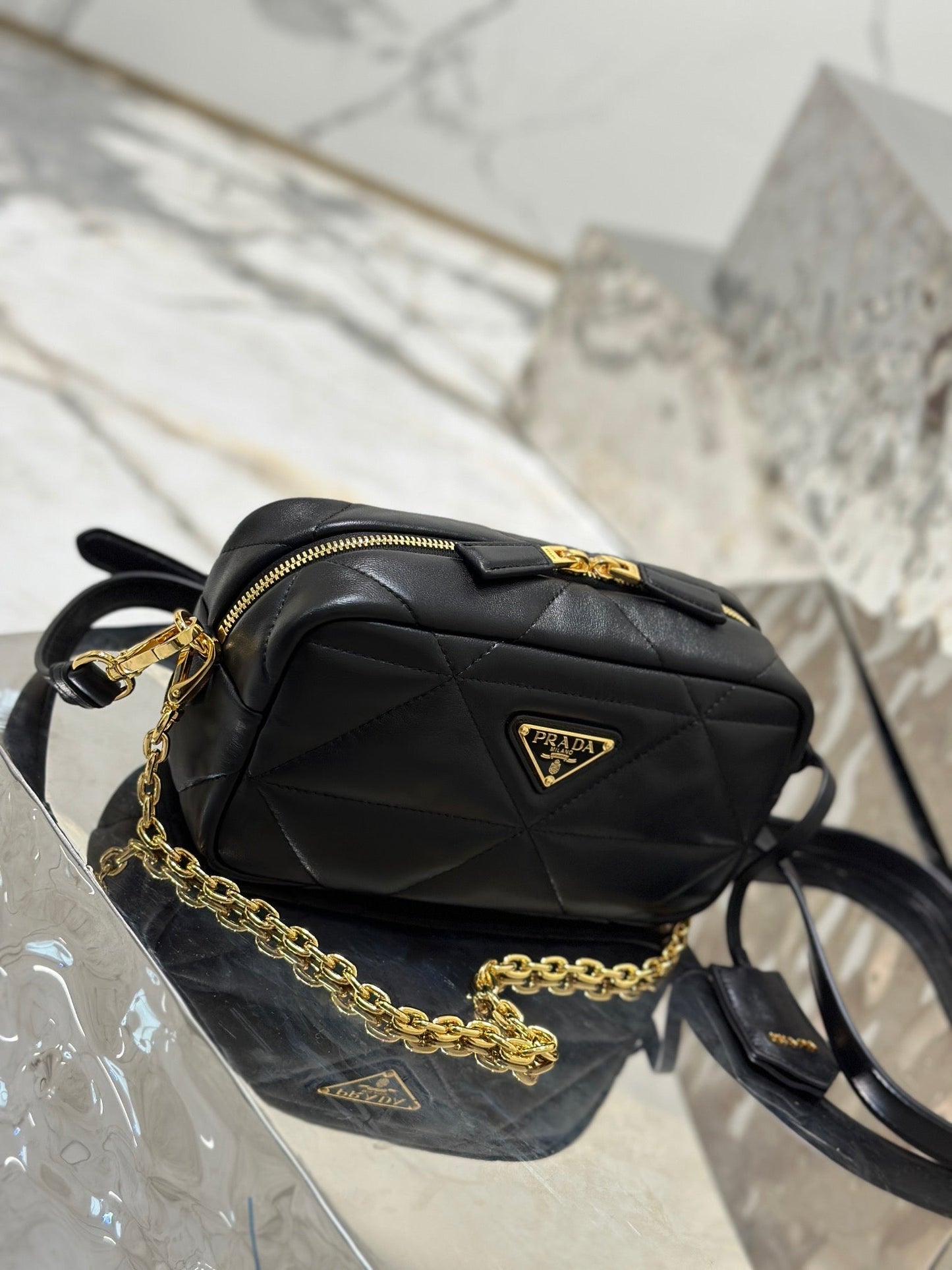 BOLSO PARA CÁMARA 22 EN PIEL DE CORDERO ACOLCHADA CON ESTAMPADO DE TRIÁNGULOS NEGROS Y HERRAJES DORADOS