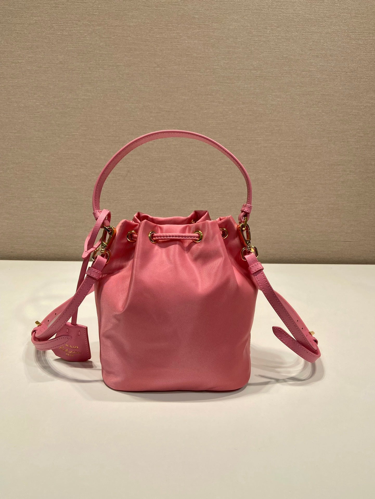 SAC SEAU 19 EN RE-NYLON ROSE BONBON ET POIGNÉE EN CUIR SAFFIANO
