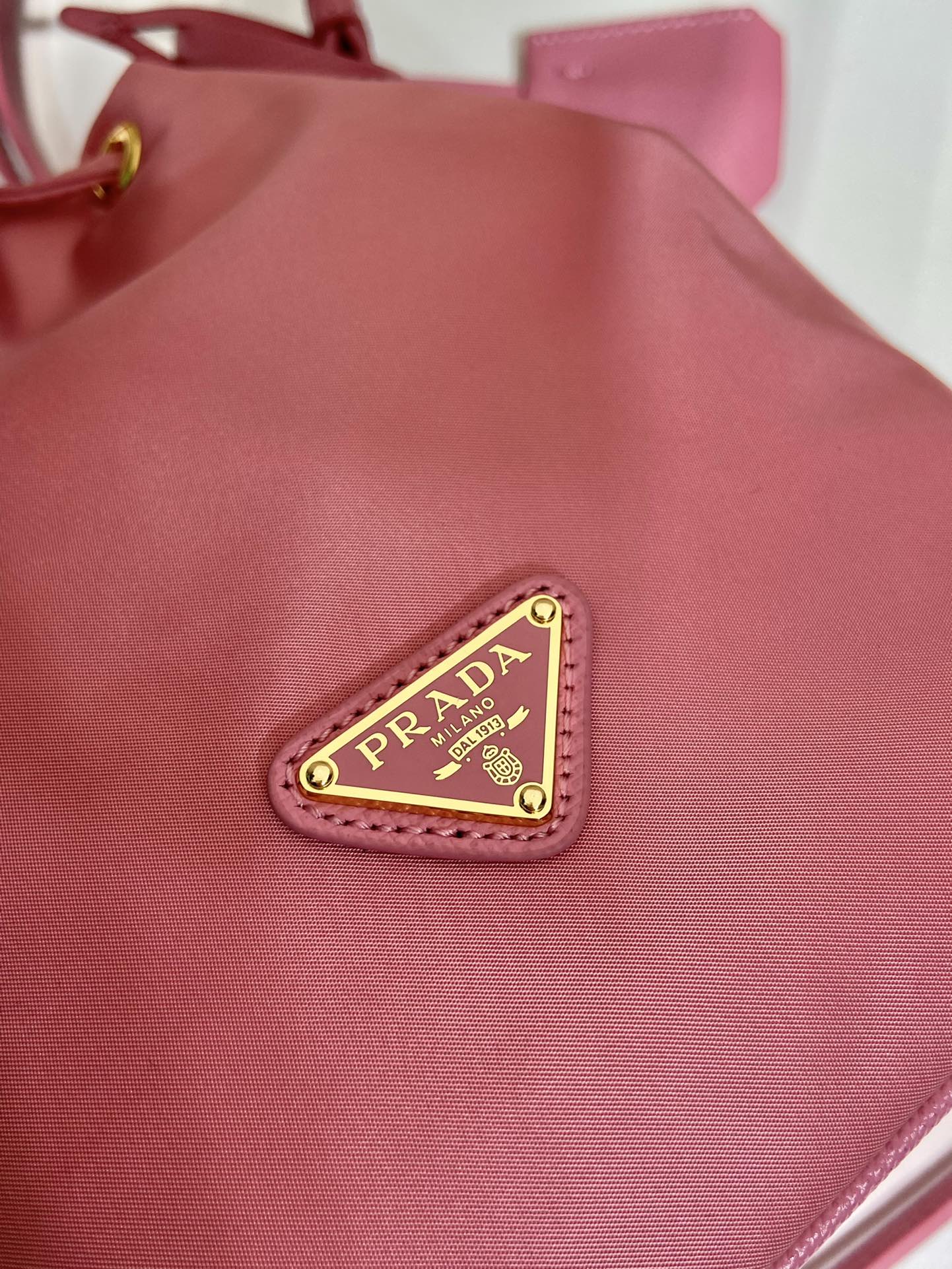 SAC SEAU 19 EN RE-NYLON ROSE BONBON ET POIGNÉE EN CUIR SAFFIANO